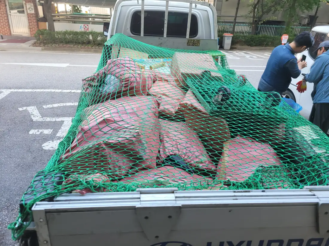 포대 폐기물에 그물을 씌워 고정한 트럭 적재함
