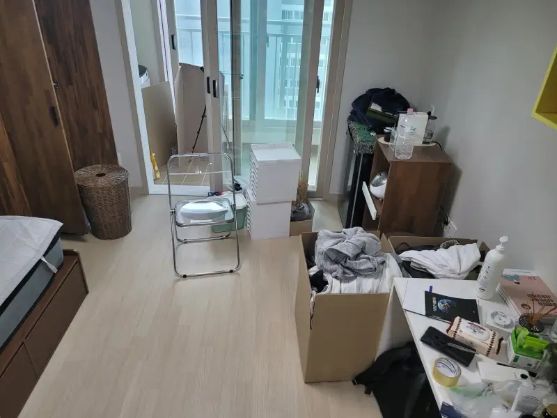 책상과 상자 위에 물건이 놓인 원룸 내부