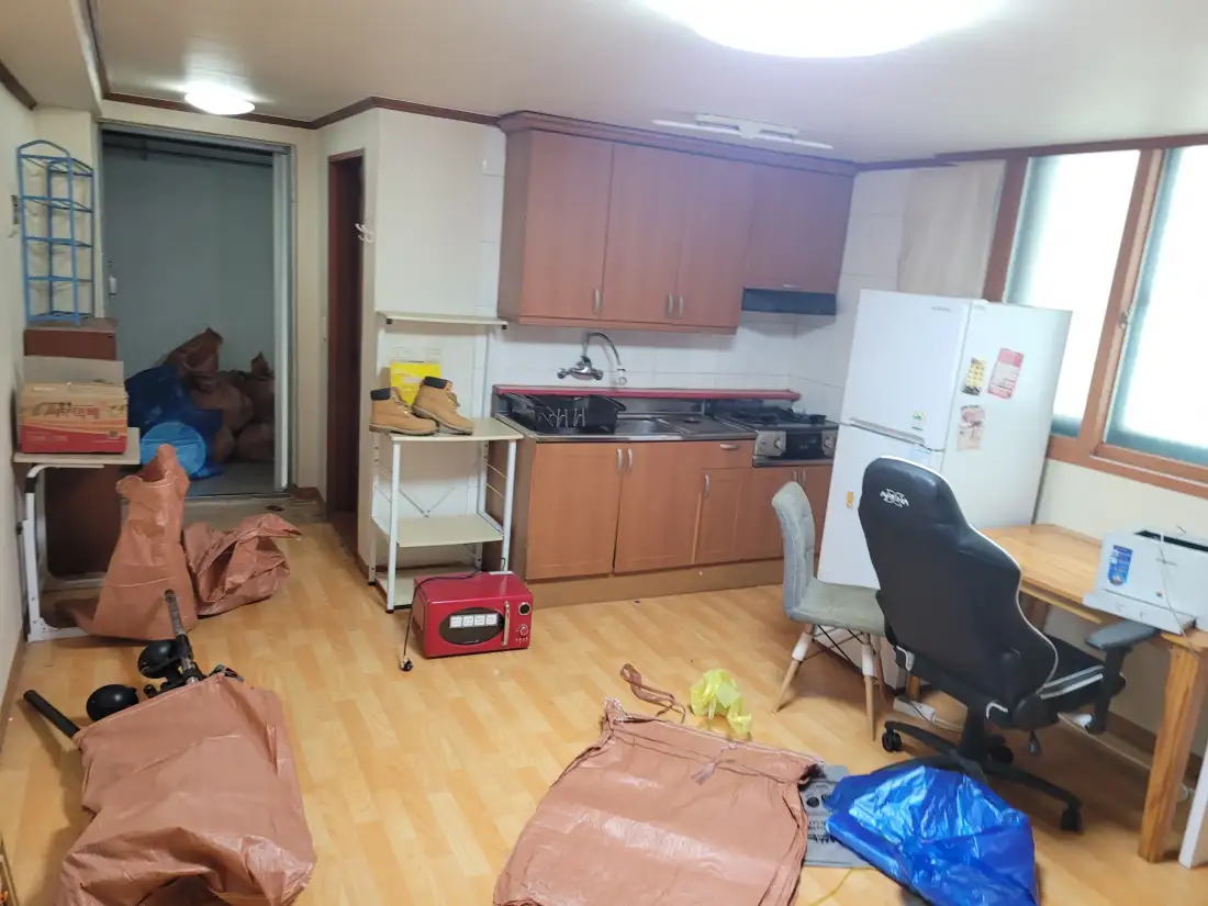 원룸 바닥에 펼친 포대에 짐을 담아 정리하는 현장